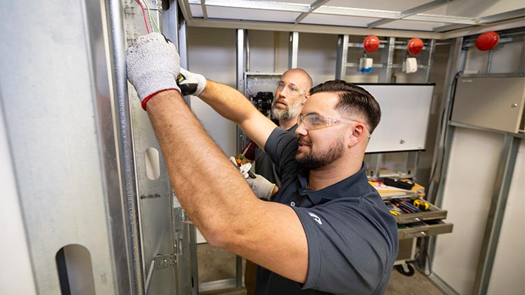 Two electricians working on wiring at the efactory.
