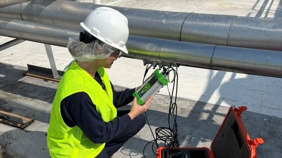 Intern wearing a hard hat conducts water flow testing during a summer internship.
