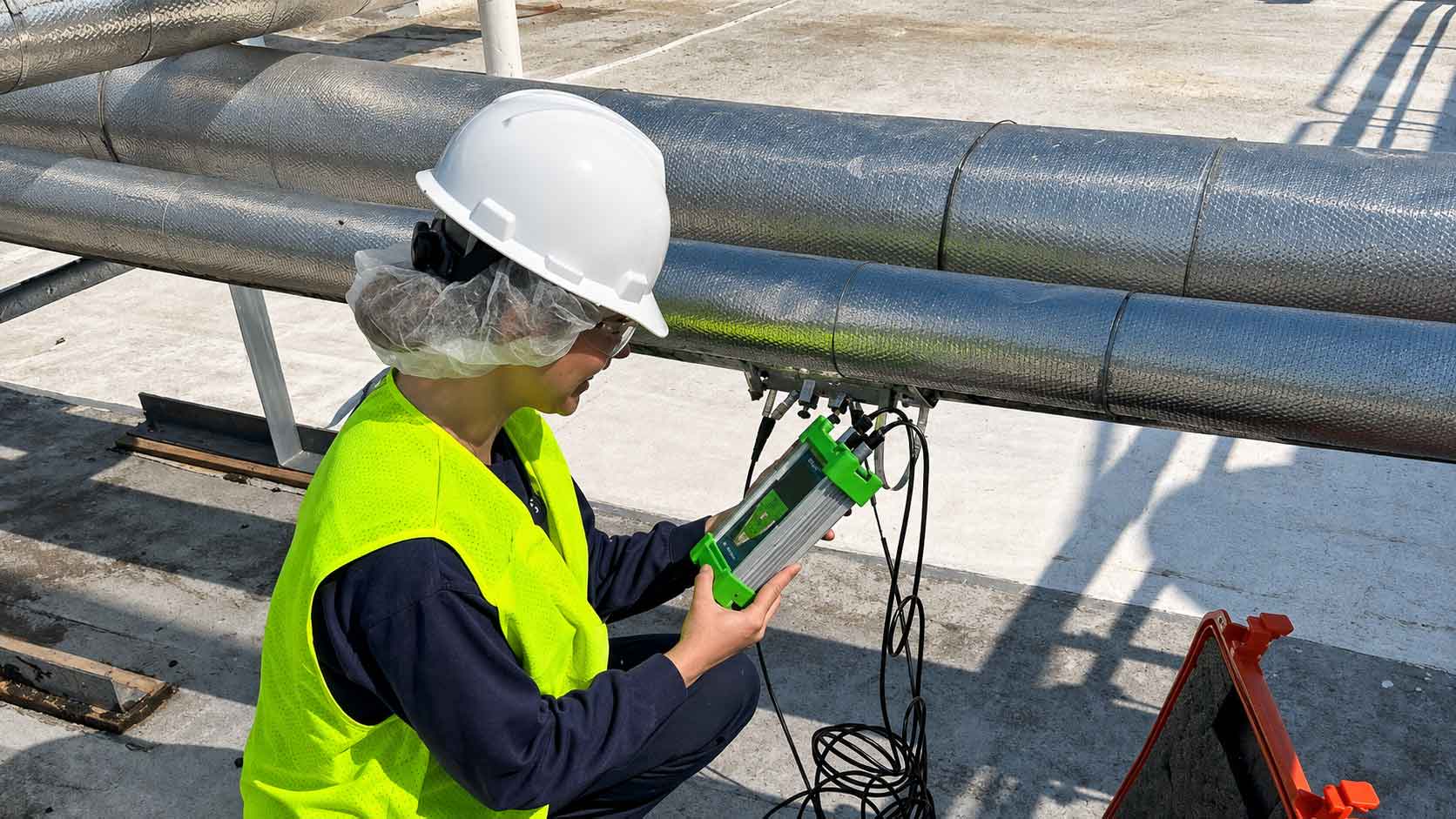 Intern wearing a hard hat conducts water flow testing during a summer internship.