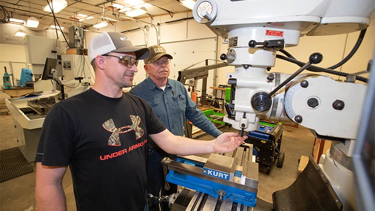 Student and instructor using equipment in a manufacturing lab.