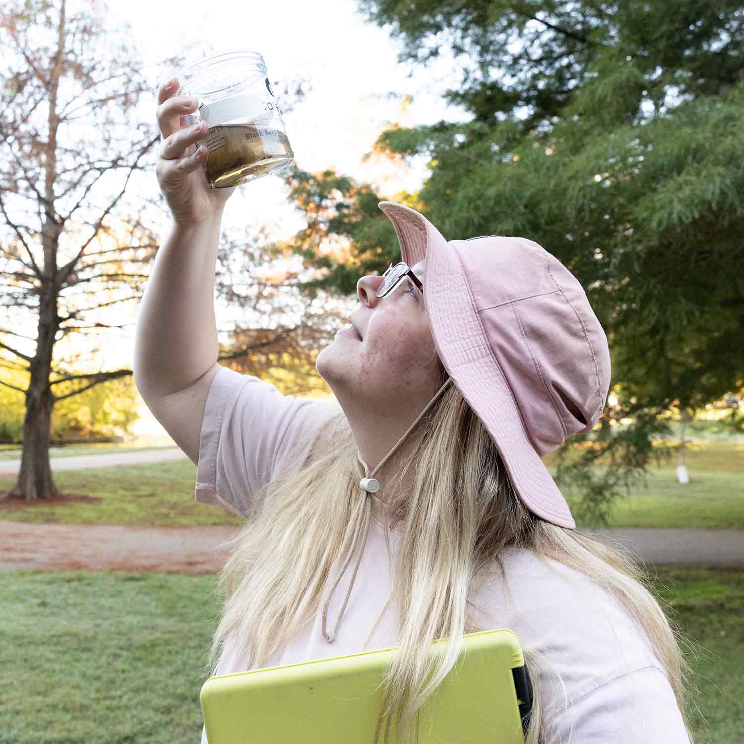 A student examines water samples in a container at Sequiota Park.