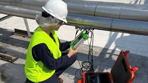 Intern wearing a hard hat conducts water flow testing during a summer internship.